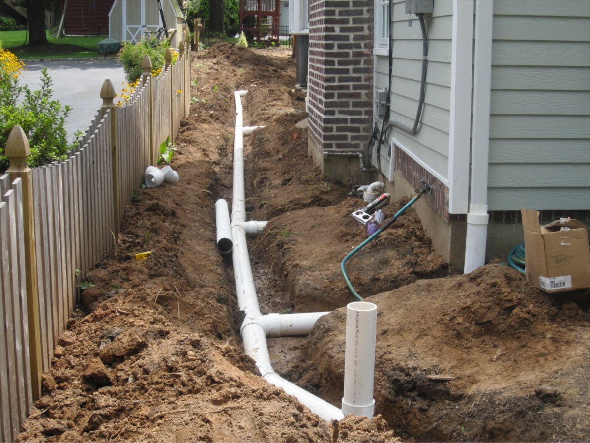 A drain pipe is being installed on the side of a house