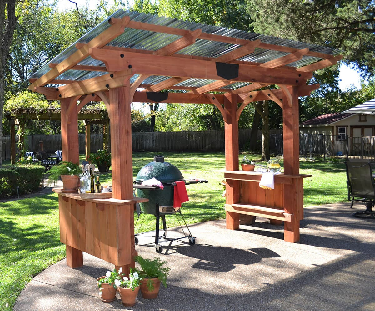 A wooden pergola is sitting on top of a patio next to a brick house.