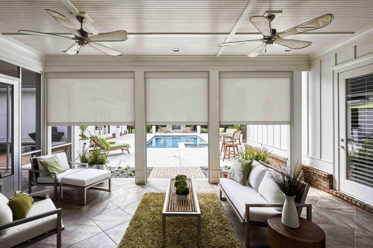 A wooden pergola is sitting on top of a patio next to a brick house.