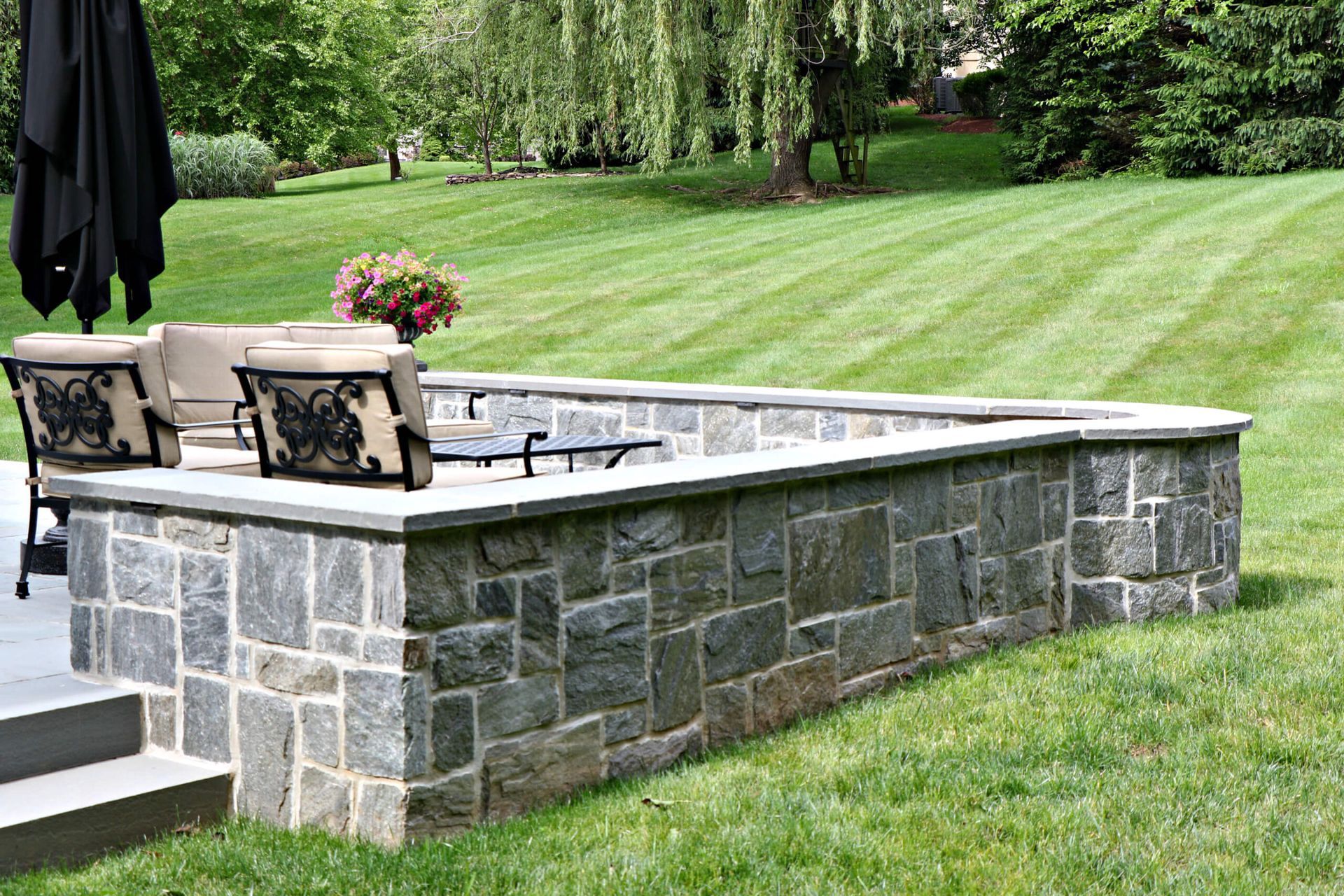 A wooden pergola is sitting next to a stone building.