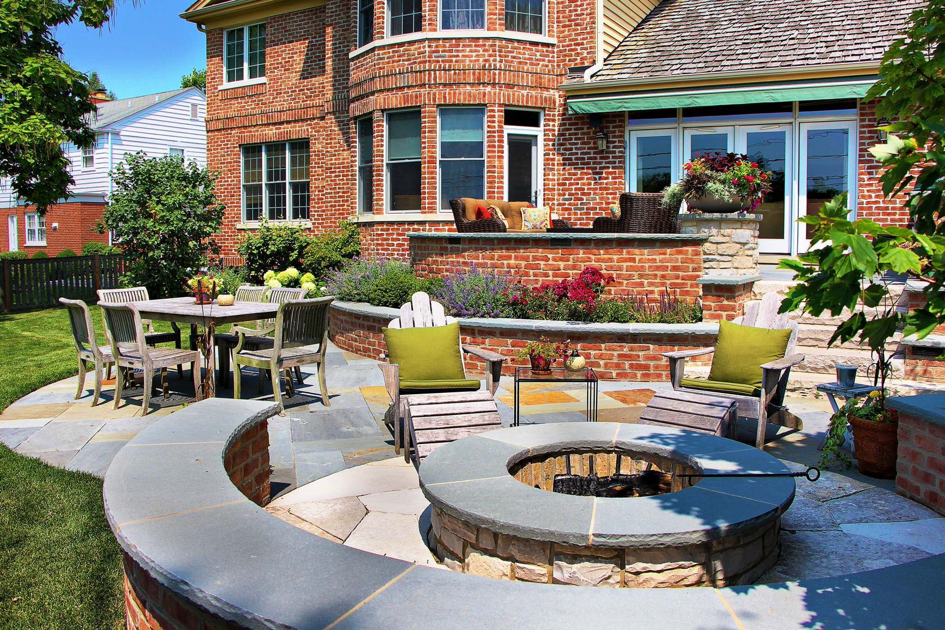 A fire pit is sitting on a patio next to a lush green field.