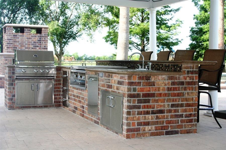 A large covered patio area with tables and chairs and a fireplace.