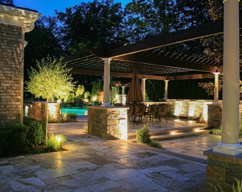 A patio with a couch , chairs , table and rug in front of a house.