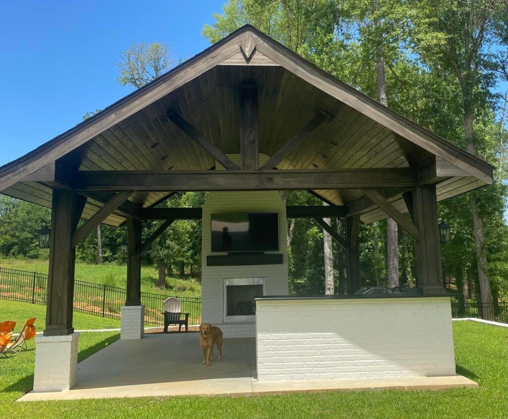 A dog is standing in front of a pavilion with a fireplace.