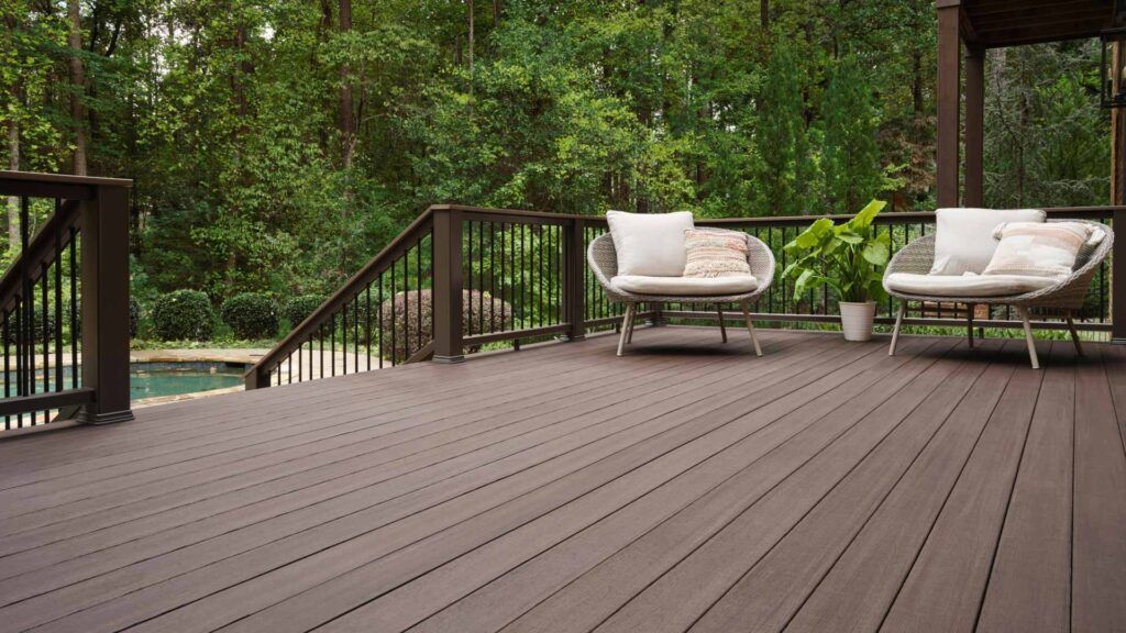 A wooden deck with chairs and a table next to a pool.