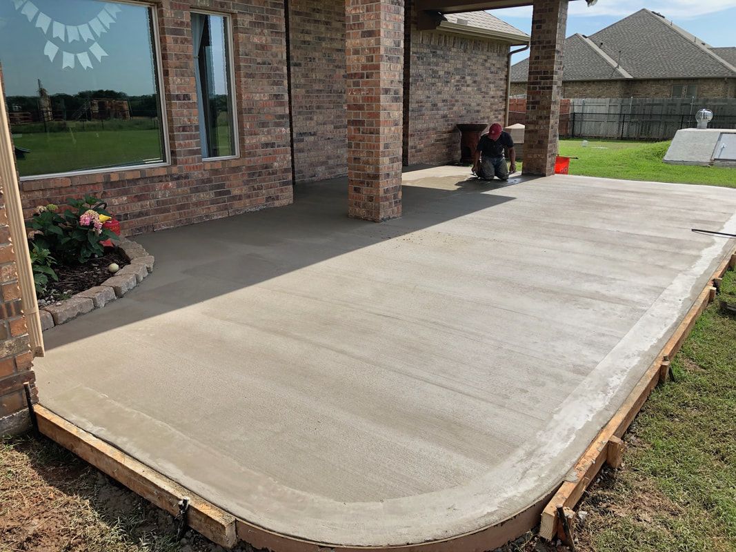 A concrete patio is being built in front of a brick house.