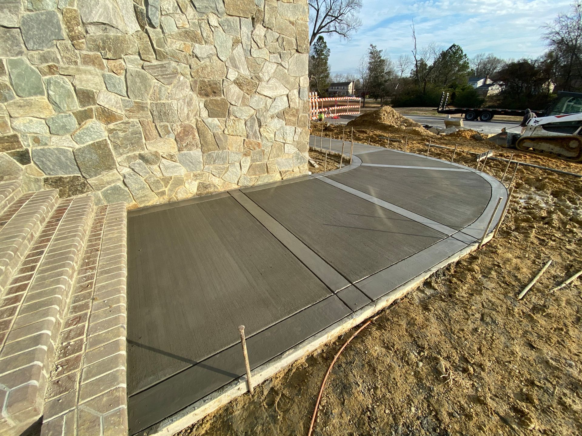 A concrete walkway is being built in front of a stone wall.