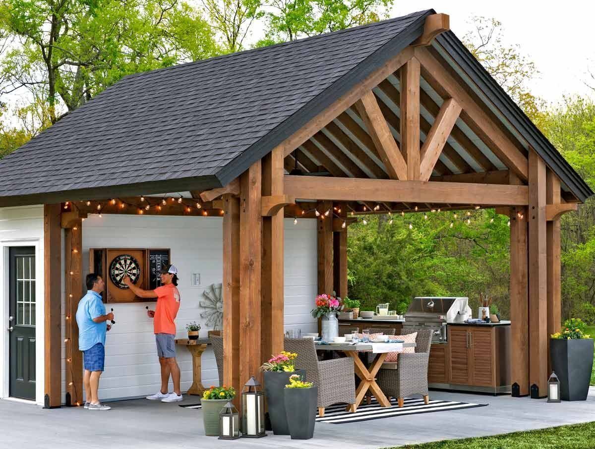 A wooden gazebo with a couch and chairs underneath it.