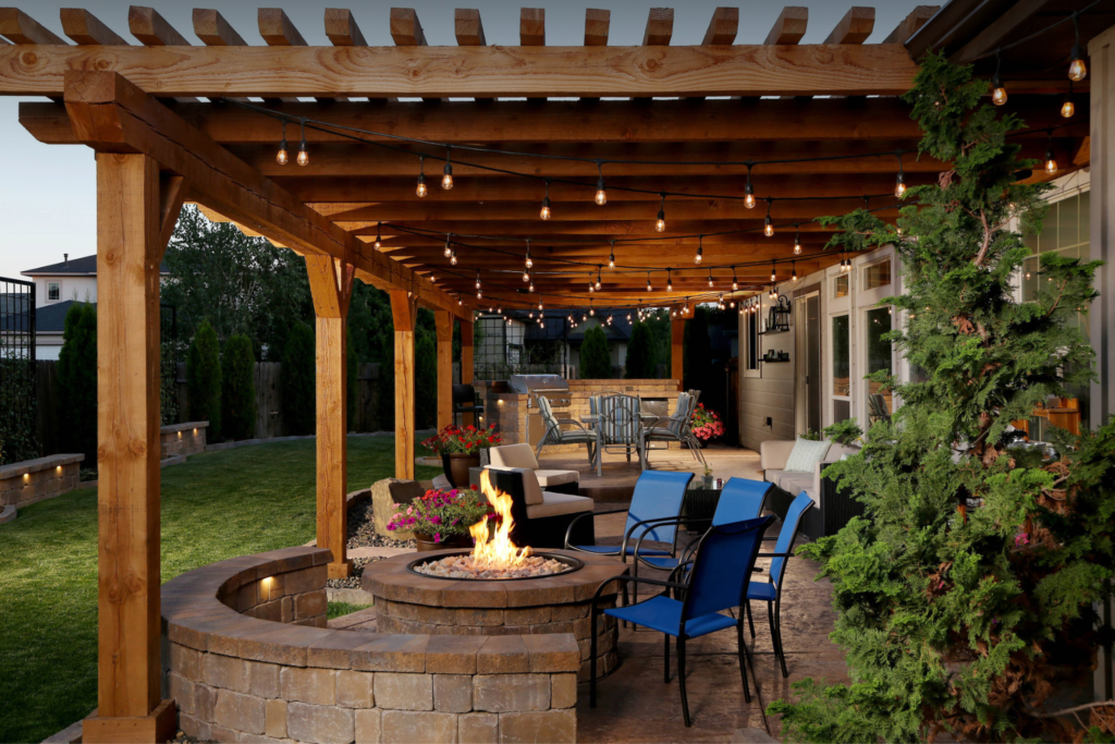 A wooden pergola is sitting on top of a patio next to a brick house.