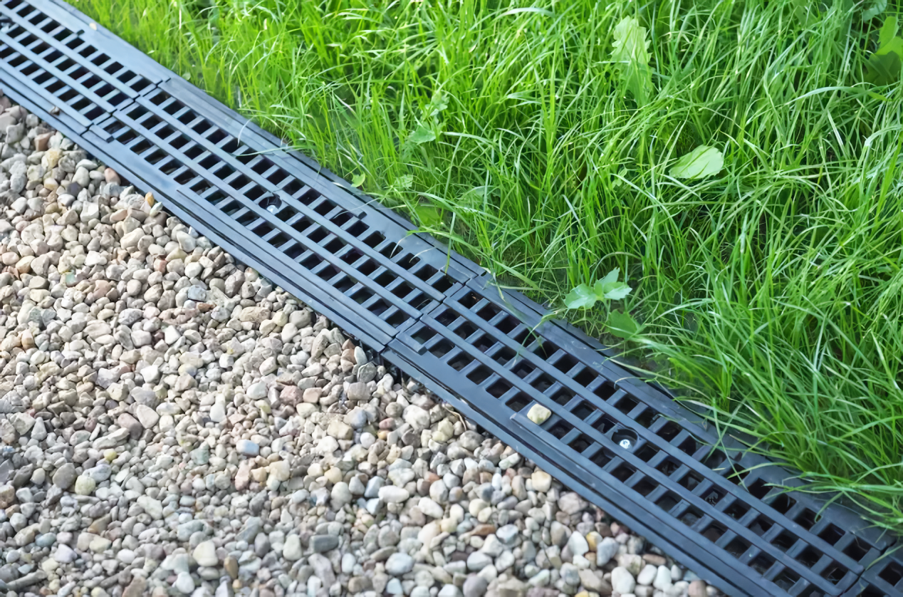 A black drain is sitting next to a lush green lawn.