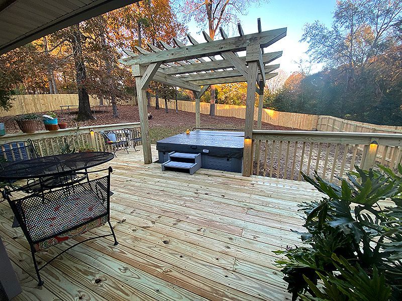 Wooden deck with pergola and hot tub overlooking a yard in autumn