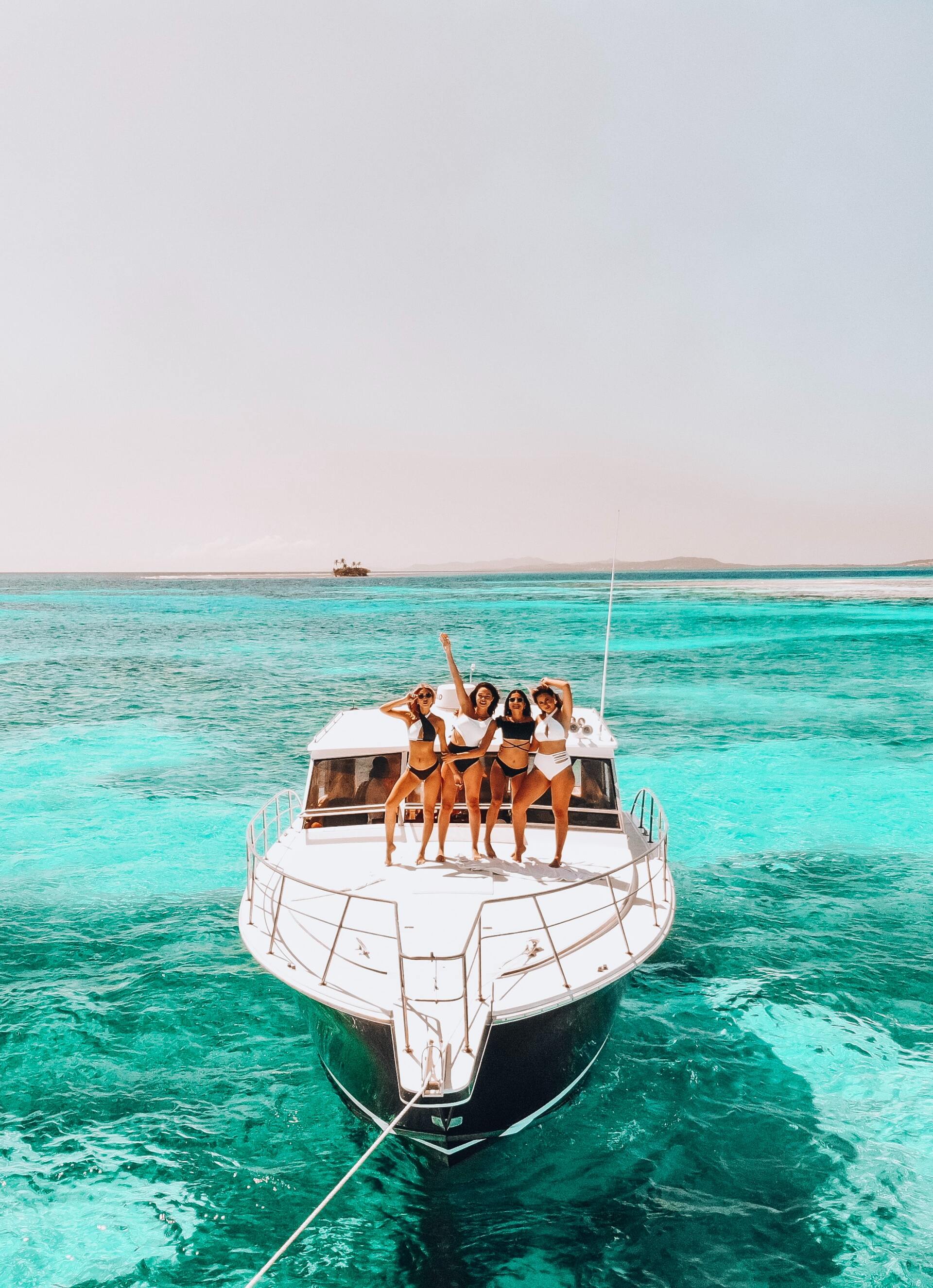 Group of friends celebrating on the back of a yacht in bright turquoise water