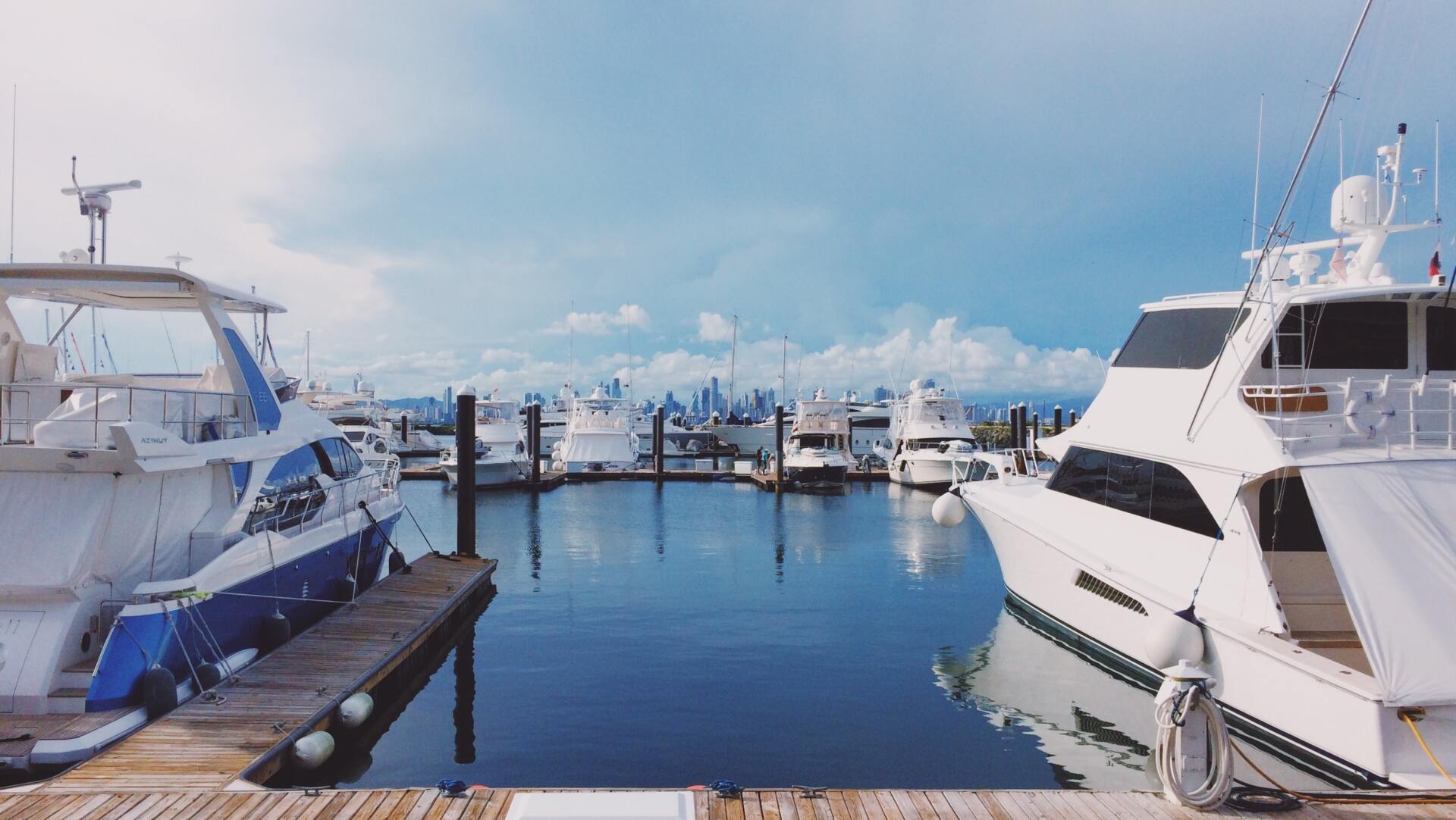 Marina filled with docked yachts under a blue sky with puffy clouds