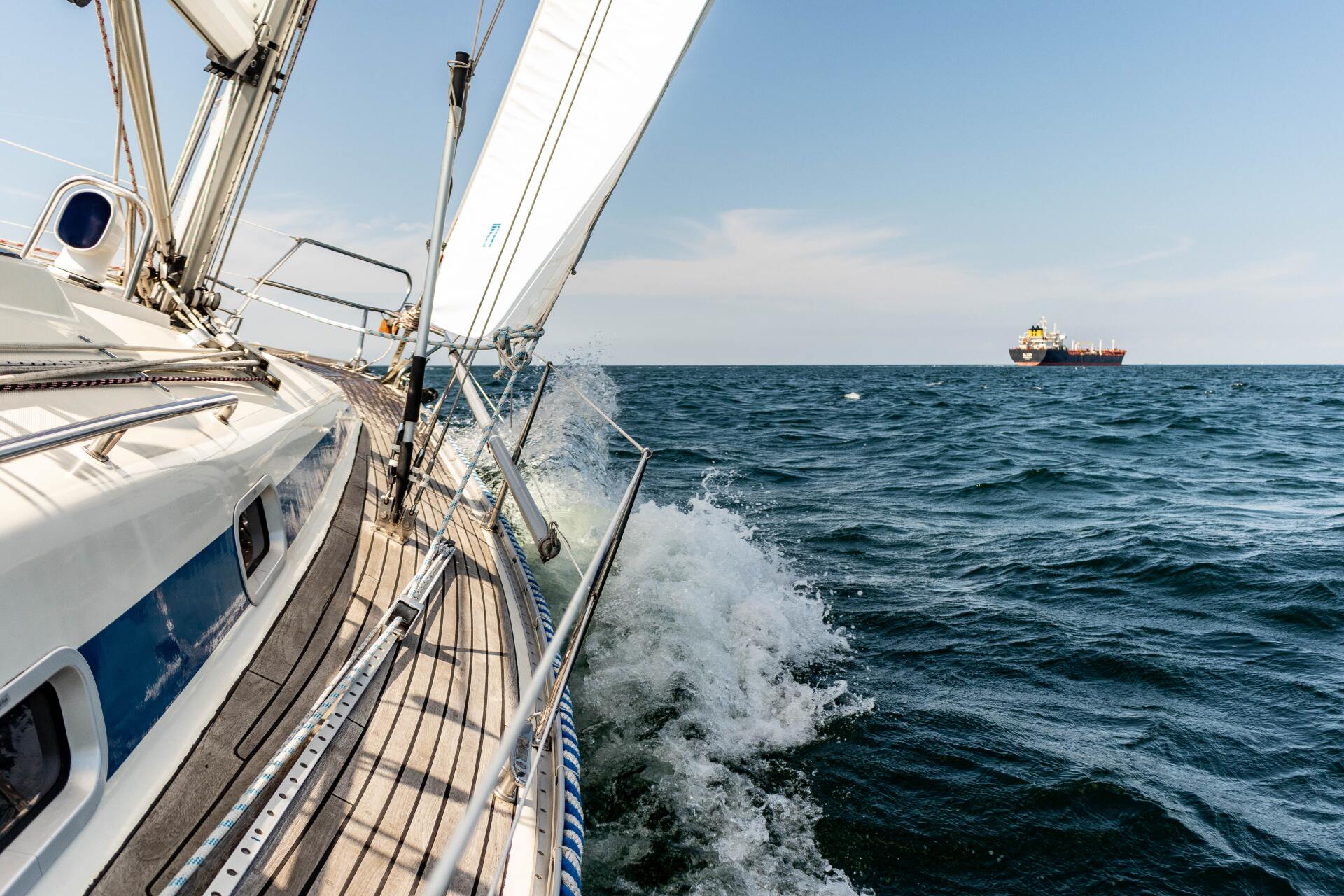 View from a sailboat cutting through ocean waves on a sunny day