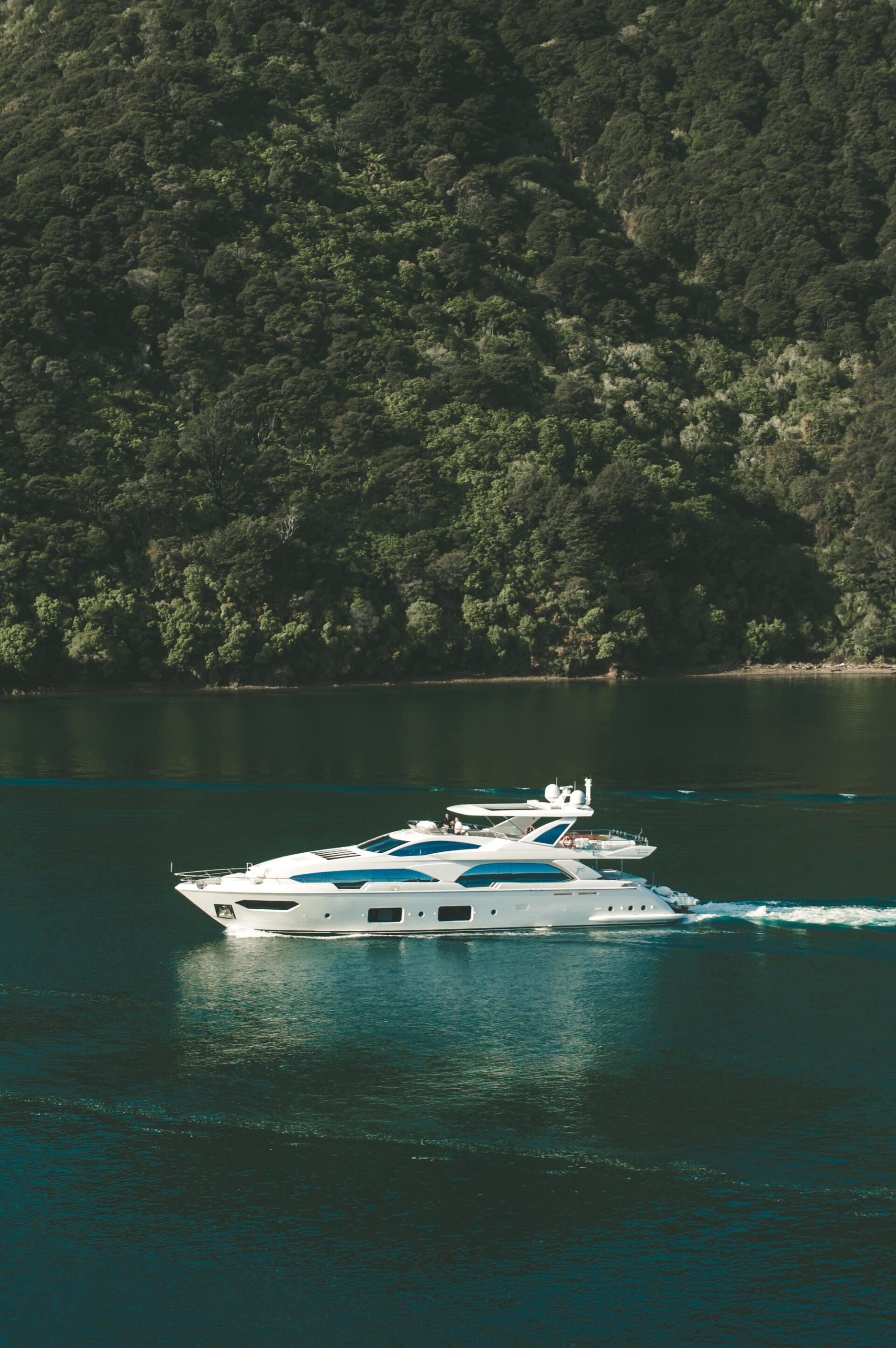 White yacht anchored near a lush green coastline