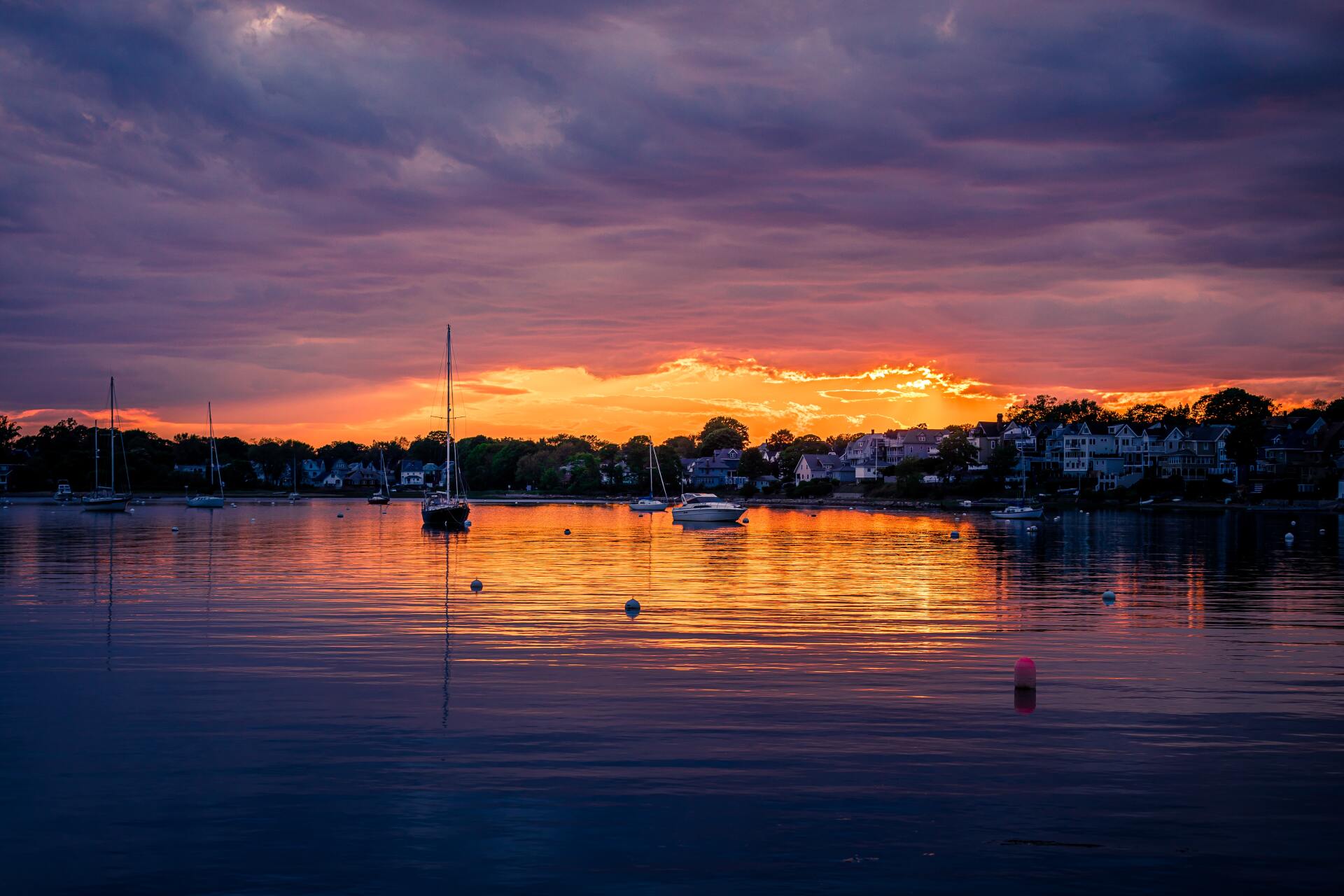 Golden sunset over a calm body of water with sailboats in the distance