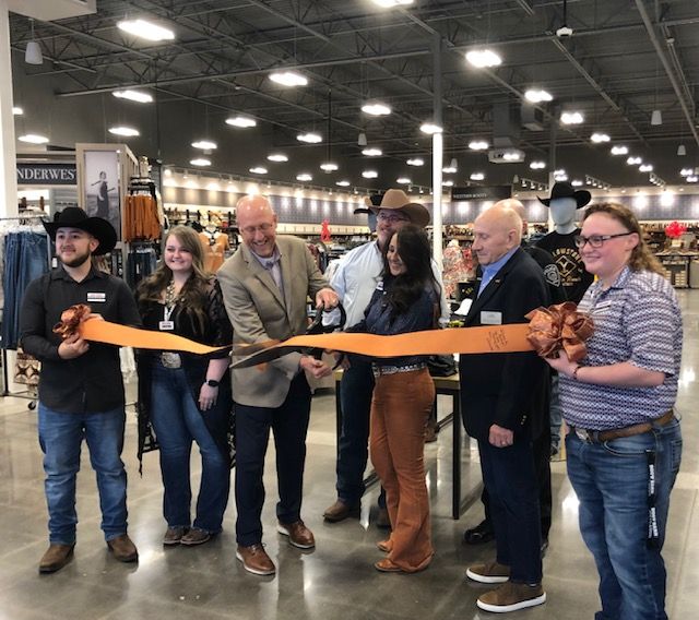 A group of people are cutting a ribbon in a store