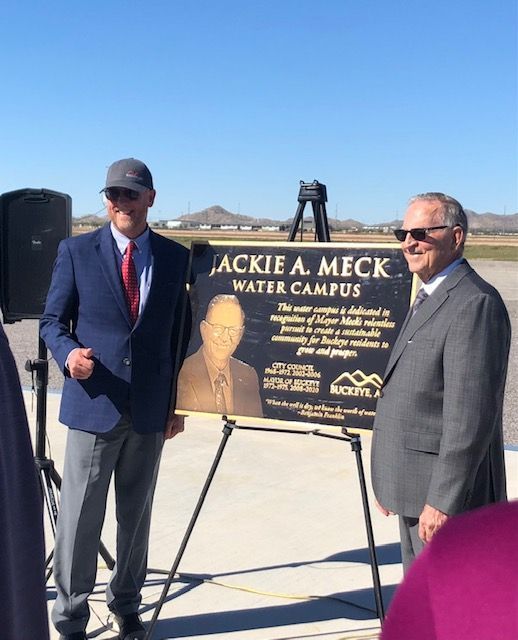 Two men standing next to a sign that says jackie a. meck water campus