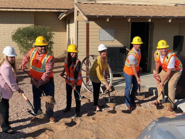 A group of construction workers are shoveling dirt in front of a house.