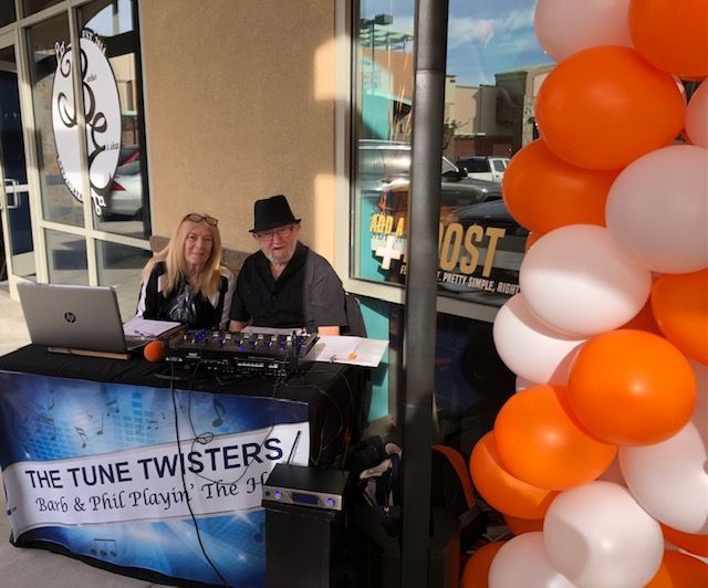 Two people sitting at a table with a sign that says the tune twisters