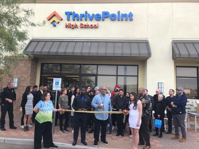 A group of people are cutting a ribbon in front of thrivepoint high school