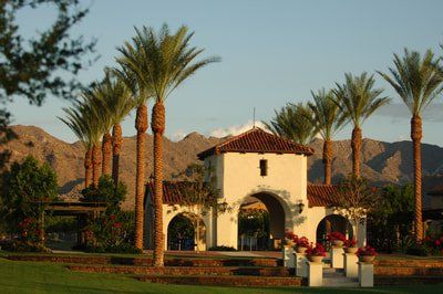 A white building with palm trees and mountains in the background
