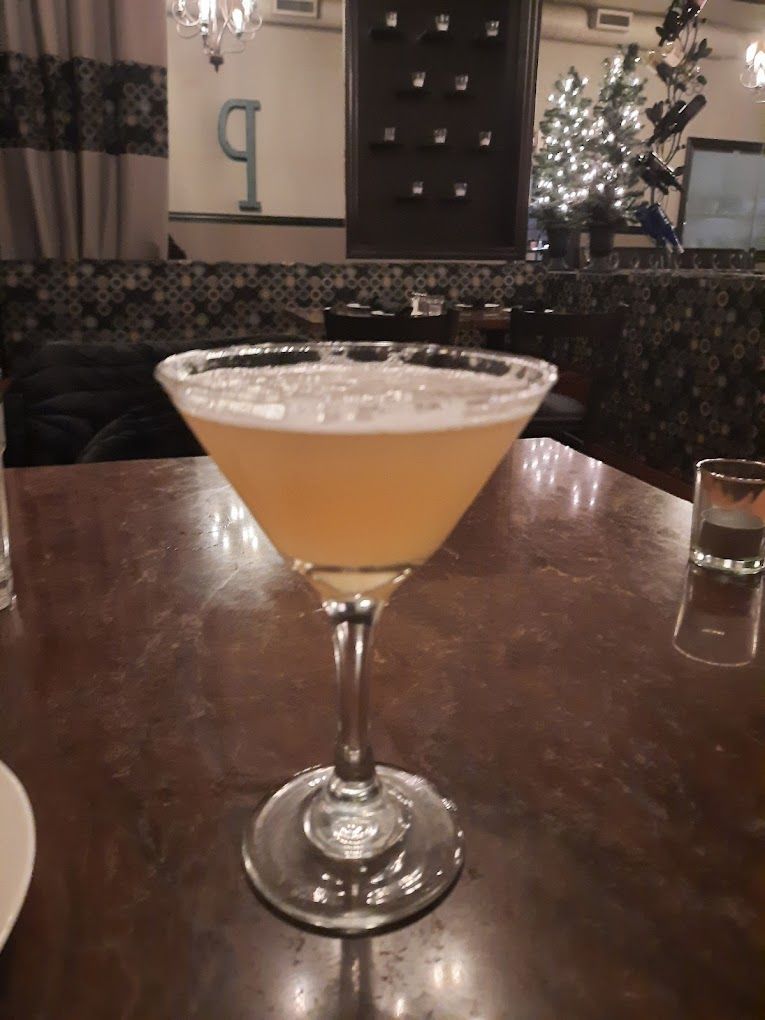 A martini glass filled with a yellow liquid on a table