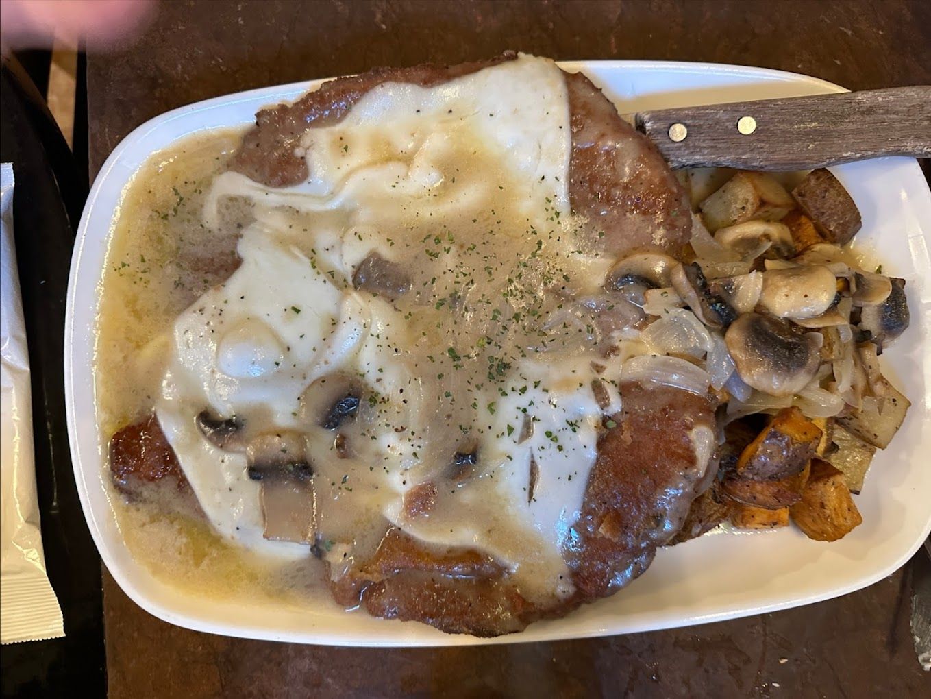 A plate of food with meat and mushrooms on a table.