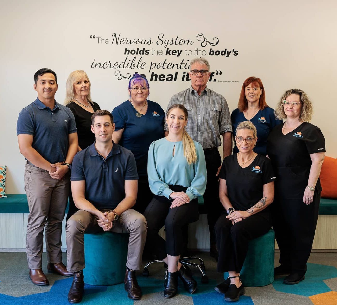 Group of Nine Healthcare Professionals Smiling in Front of A Wall with A Quote — Grays Chiropractic & Wellness In Ooralea, QLD