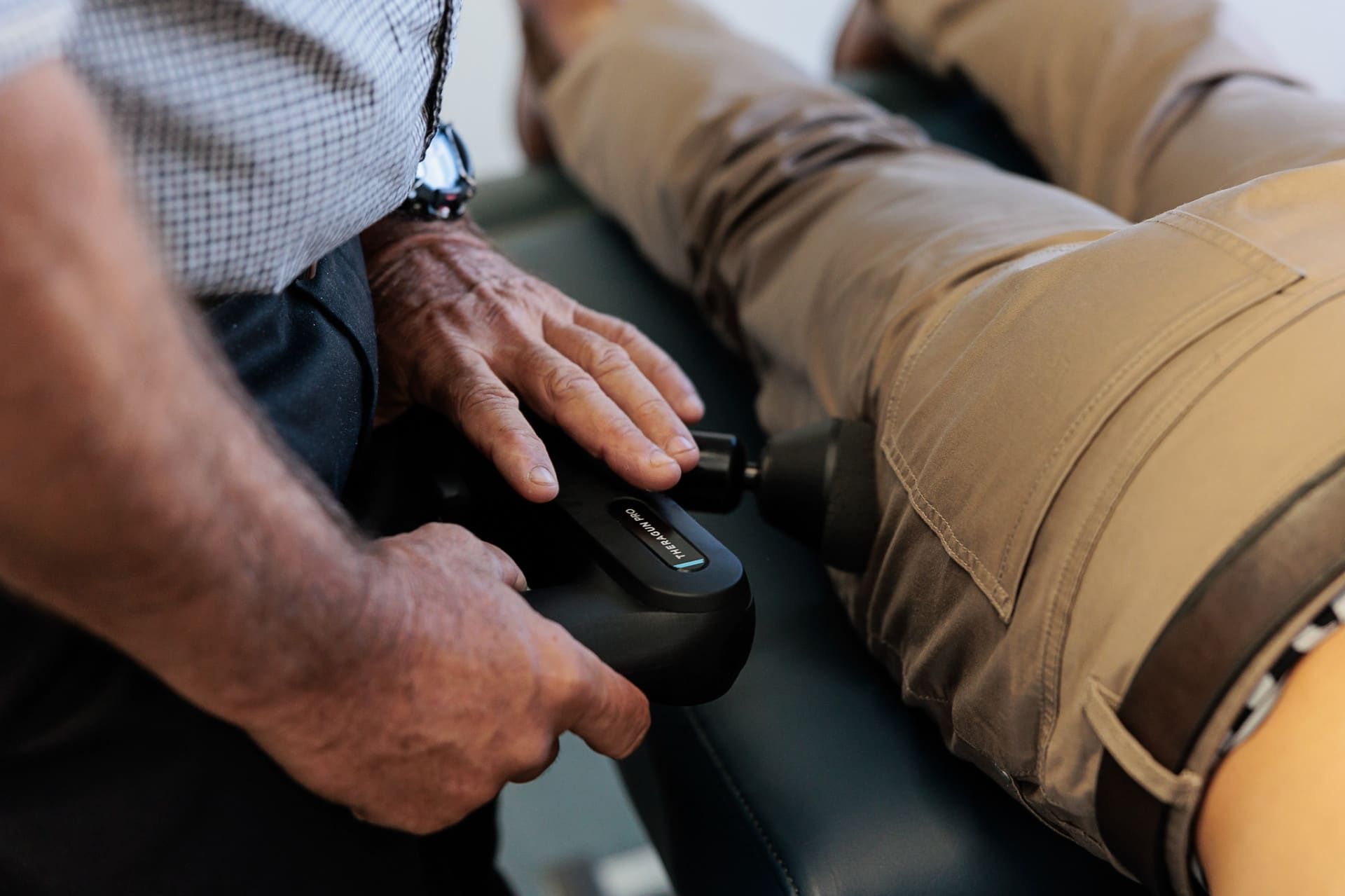 Person Using a Handheld Device on A Person's Leg; Indoors, on An Examination Table — Grays Chiropractic & Wellness In Marian, QLD