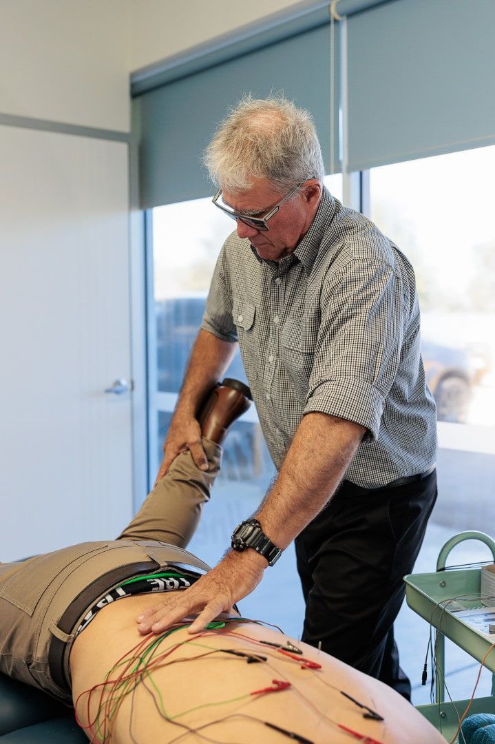 Man Performing a Medical Procedure on A Patient's Back. Wires Attached, Indoors — Grays Chiropractic & Wellness In Walkerston, QLD