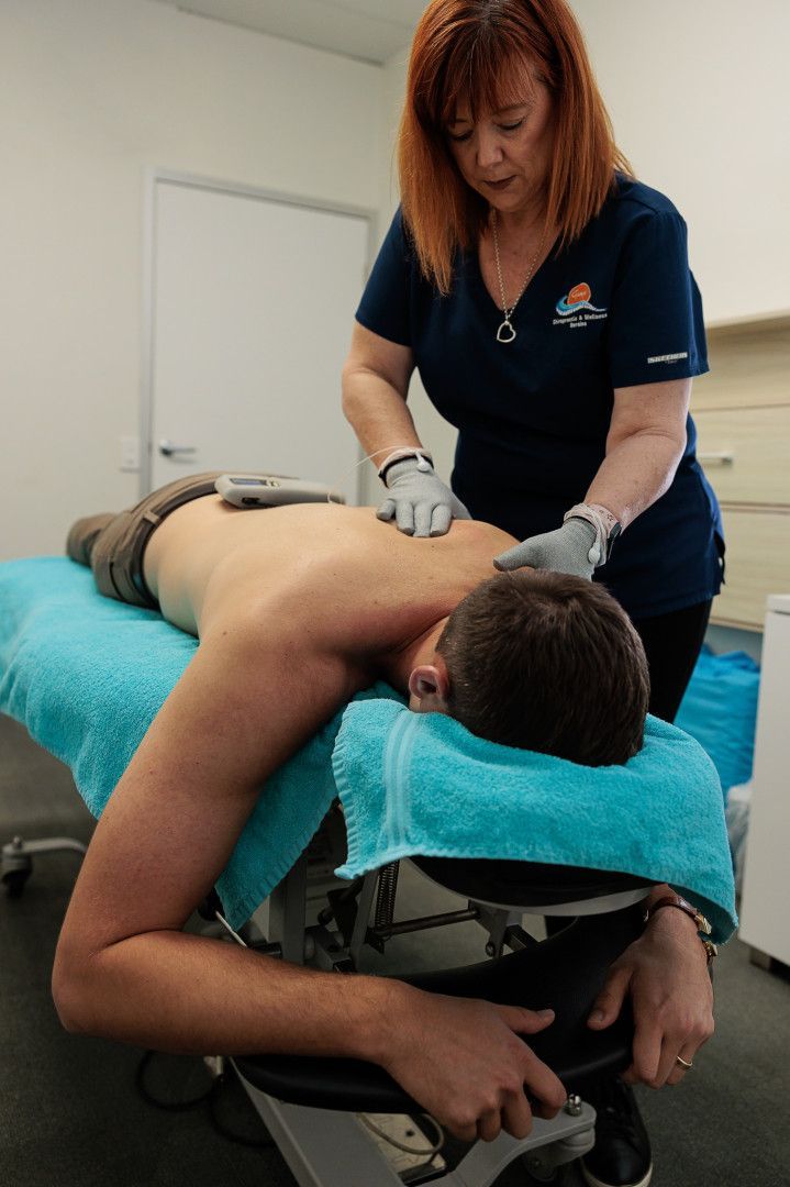 Woman Giving Back Massage to A Man on A Teal-Covered Table — Grays Chiropractic & Wellness In Ooralea, QLD