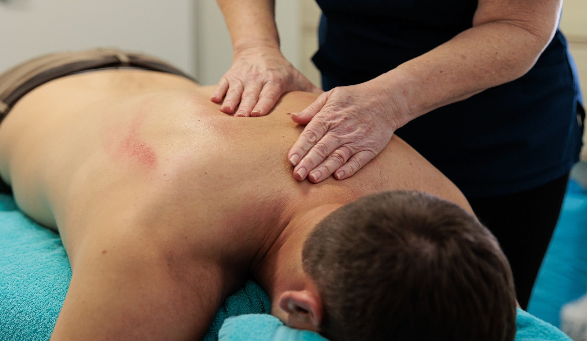 Person Receiving a Back Massage. a Therapist's Hands Massage the Back of A Person Lying on A Massage Table — Grays Chiropractic & Wellness In Ooralea, QLD