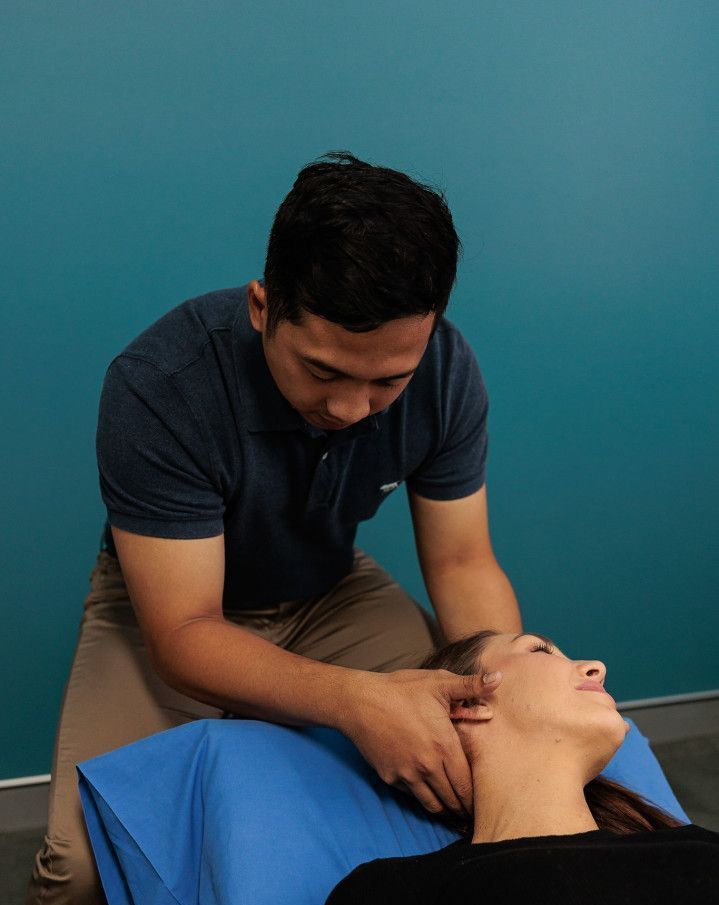 A Man Giving a Woman a Neck Massage; Both Are in A Room with A Blue Wall — Grays Chiropractic & Wellness In Paget, QLD