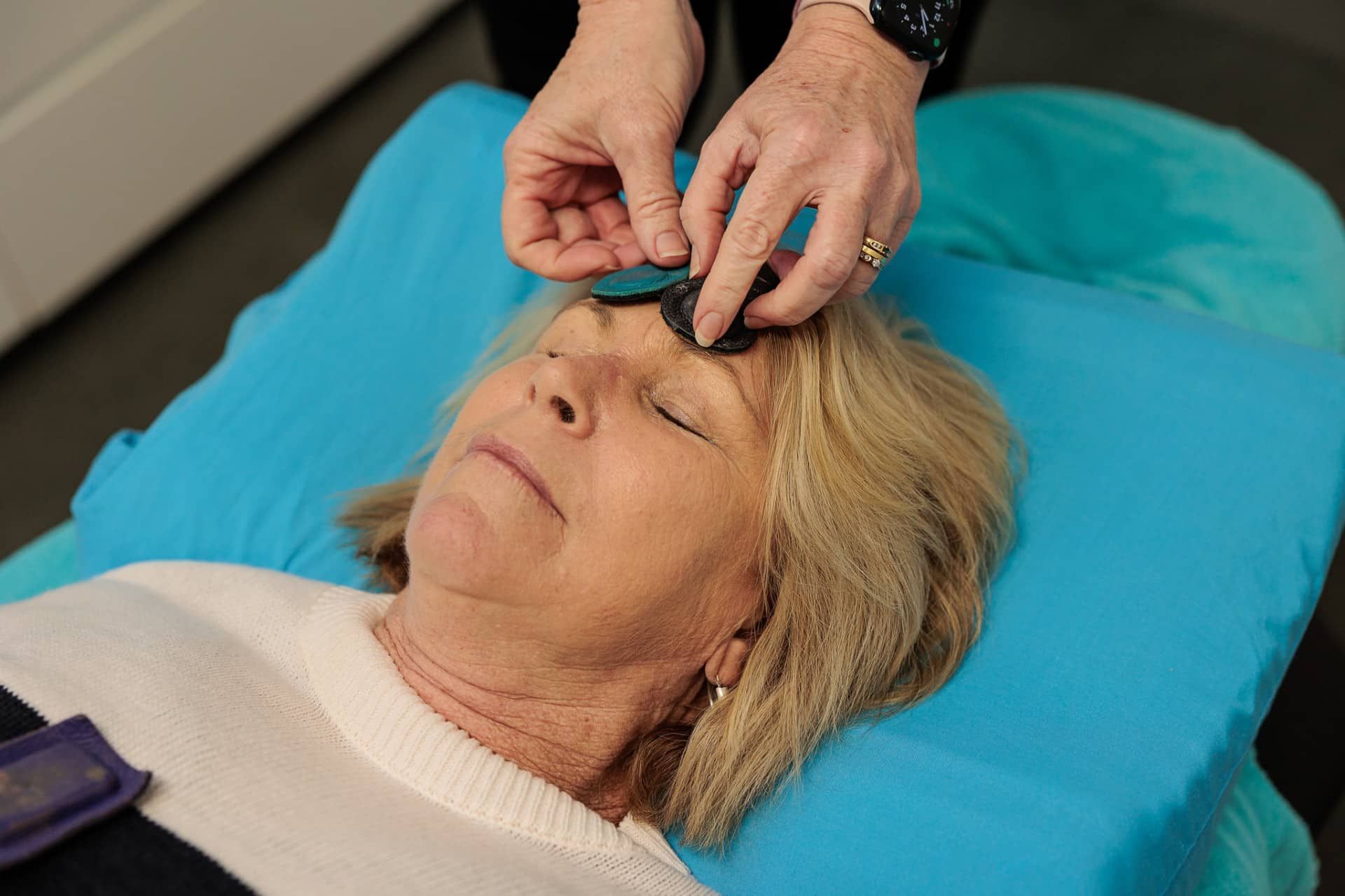 Woman Receiving a Wellness Treatment with Items Being Placed on Her Forehead While Lying Down — Grays Chiropractic & Wellness In Ooralea, QLD