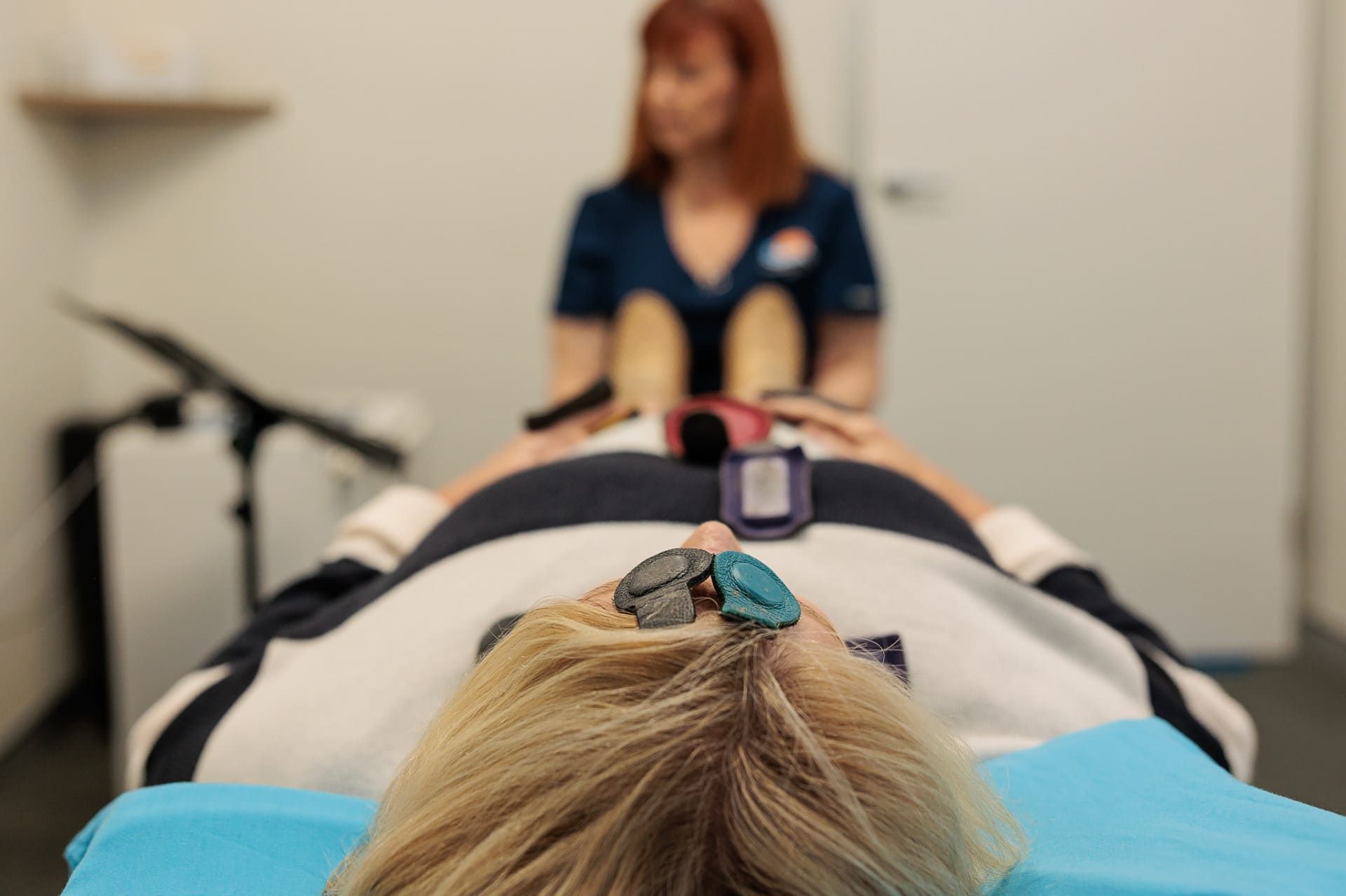 Woman Undergoing Treatment, Electrodes on Head, Clinician in Background — Grays Chiropractic & Wellness In Walkerston, QLD