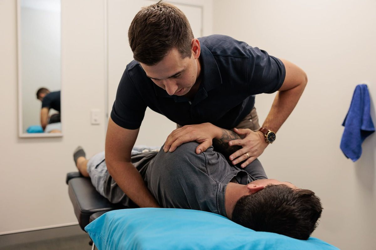 Chiropractor Adjusting a Patient's Spine While the Patient Lies on A Table in An Exam Room — Grays Chiropractic & Wellness In Ooralea, QLD
