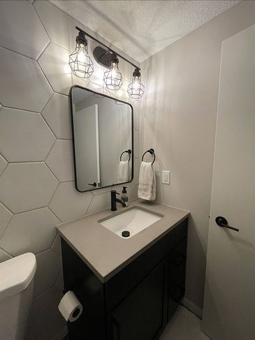 A bathroom with a sink , mirror and toilet.