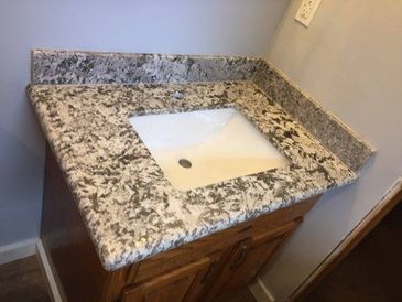 A bathroom vanity with a granite counter top and a sink.