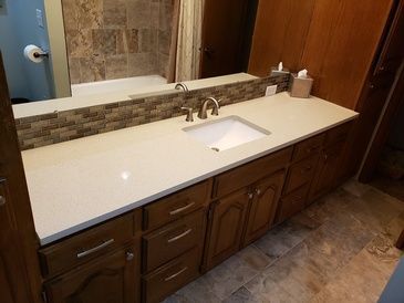 A bathroom with a sink , mirror , cabinets and drawers.