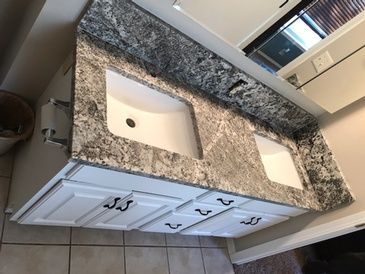 A bathroom vanity with two sinks and a granite counter top.