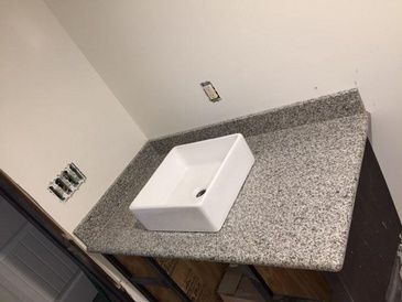 A bathroom sink is sitting on top of a granite counter top.