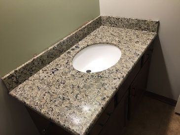 A bathroom sink with a granite counter top and a white sink.
