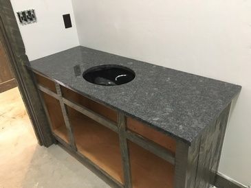 A bathroom vanity with a granite counter top and a sink.
