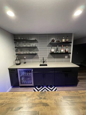 A kitchen with a sink , refrigerator , and shelves.