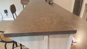 A kitchen counter with a triangle shaped counter top and two chairs.