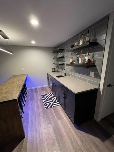 A kitchen with a bar and shelves filled with bottles of alcohol.