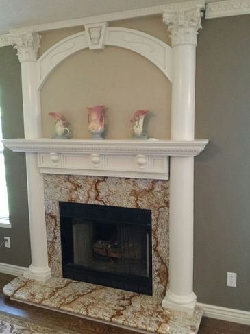 A fireplace with a mantle and columns in a living room.