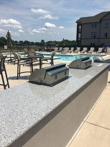 A grill is sitting on a counter next to a pool.