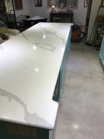 A long white counter top in a kitchen with blue cabinets.